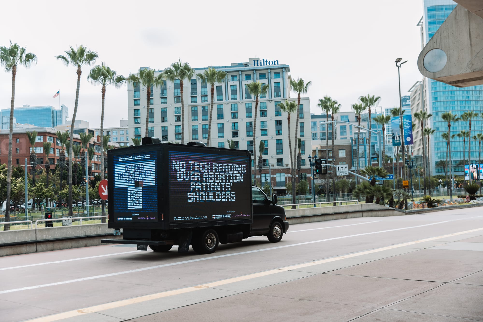 A LED sign truck reads “No tech reading over abortion patients’ shoulders” on the side, and “Defend the Internet Archive” on the back panel.